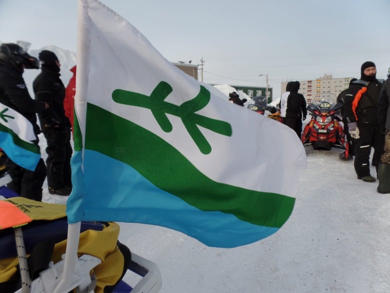 Flag with horizontal white, green and blue stripes and a green sprig of spruce adorning the white stripe. 