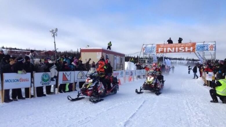 Snowmobiles at the finish line with crowd