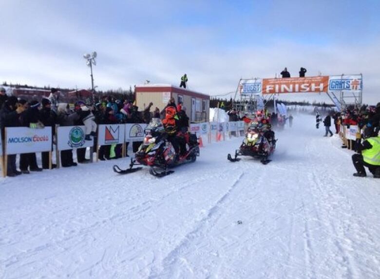 Snowmobiles at the finish line with crowd