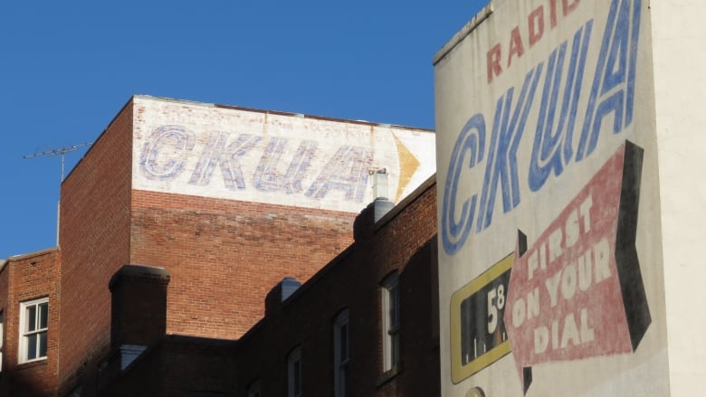 The letters C-K-U-A are painted on a red brick building.