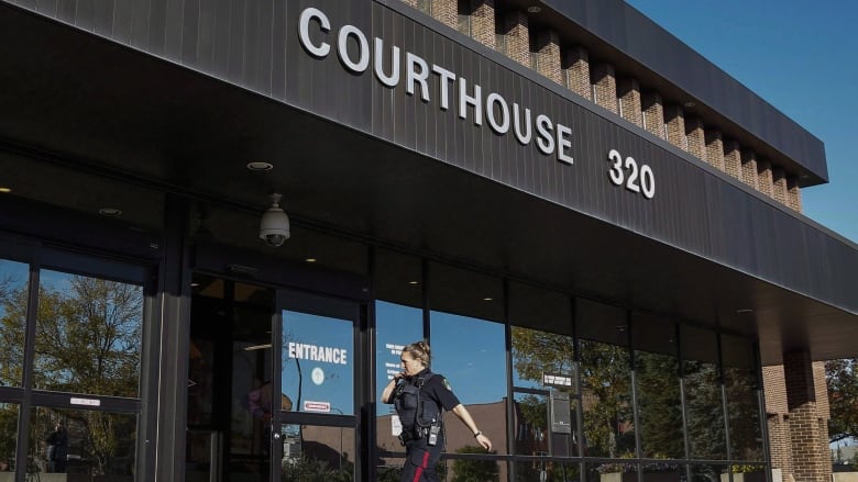 A police officer walks into a courthouse.