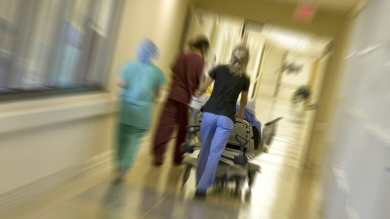 A person pushes a stretcher down a hallway.