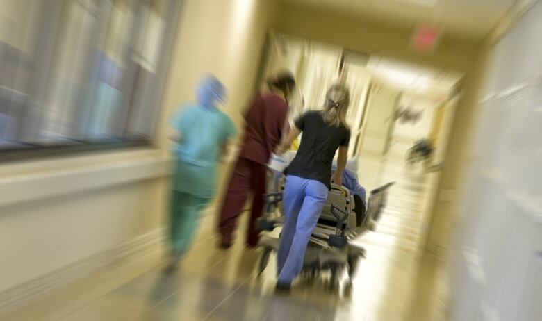 A person pushes a stretcher down a hallway.