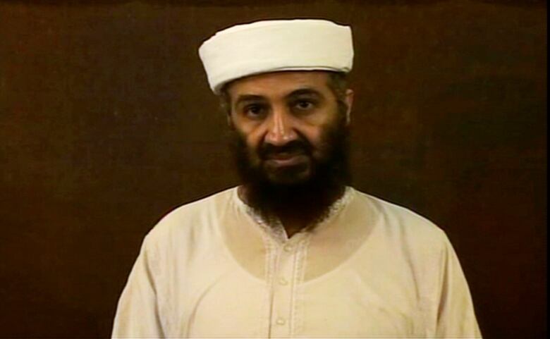 A bearded man in a white hat and shirt.