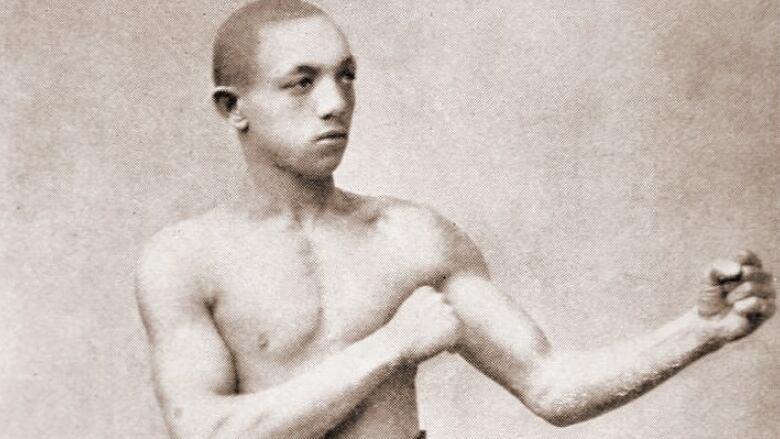 An old image of a Black boxer holding a fighting pose