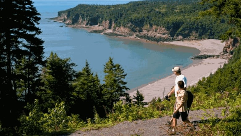 A couple hike in front of a vista