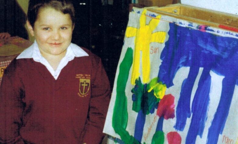 A young boy standing beside a painting