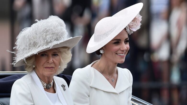 Two women in formal attire ride in a horse carriage.