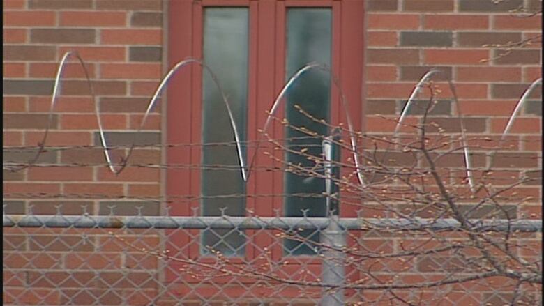 A red brick building surrounded by metal fencing and razor wire.