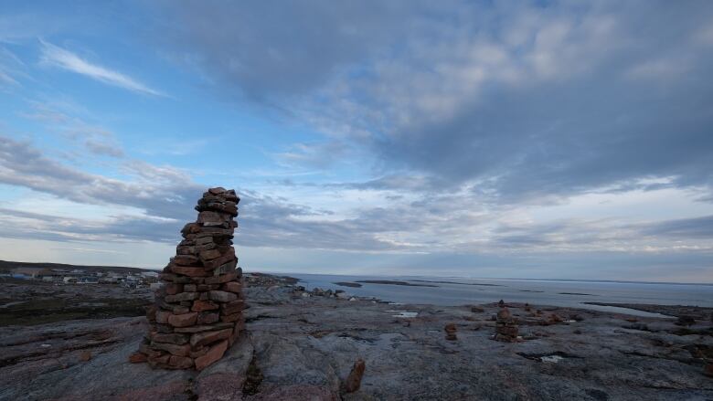 Rock formation, blue sky, buildings in background.