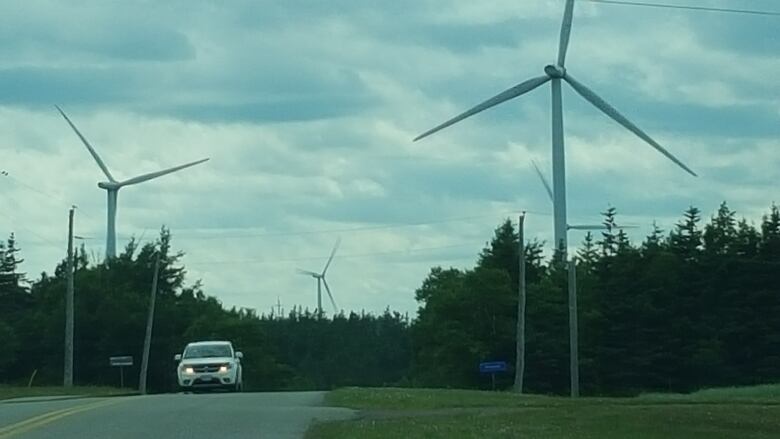 View of Hermanville wind farm with vehicle driving on highway.