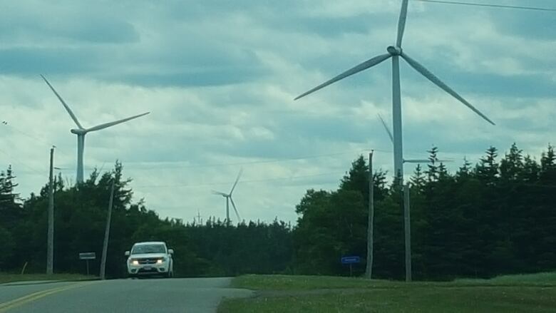 View of Hermanville wind farm with vehicle driving on highway.