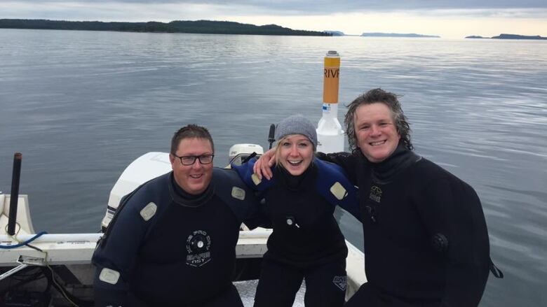 Three people sit and smile on a boat.