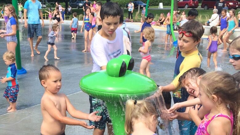 Children play at an outdoor water splash pad.