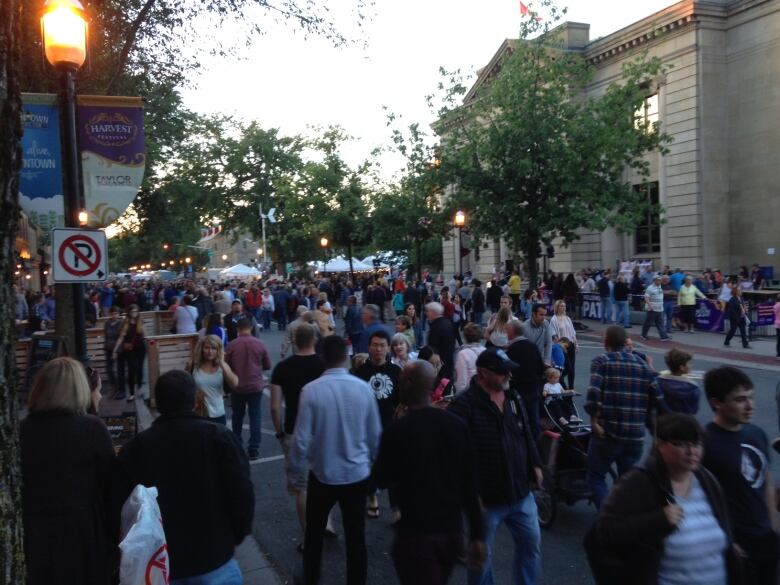 A crowded Fredericton street at dusk during Harvest festival.