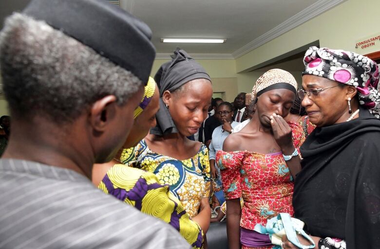 Three women stand next to each other crying