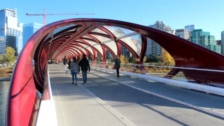 Pedestrians walk across the bright red Peace Bridge in Calgary.