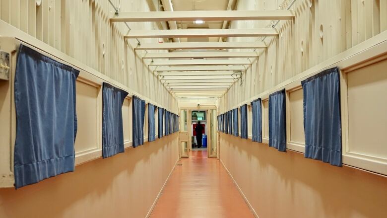 Blue privacy curtains cover cell doors in a cell block of a jail.