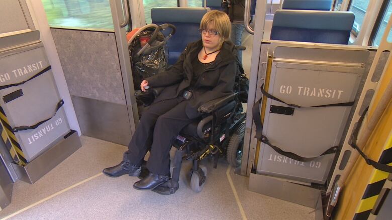 A woman in a wheelchair rides an empty GO train.