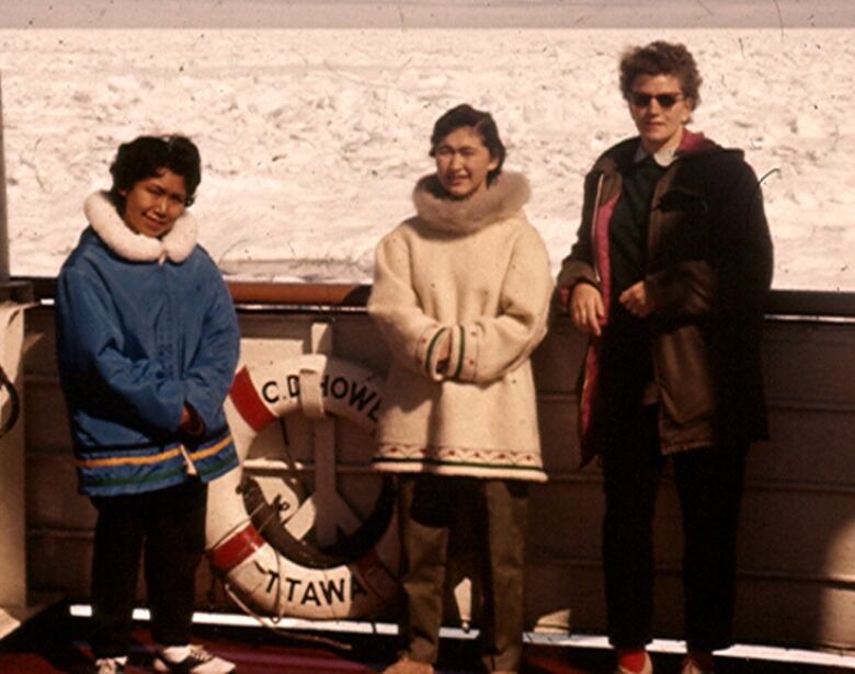 Three women stand on ship