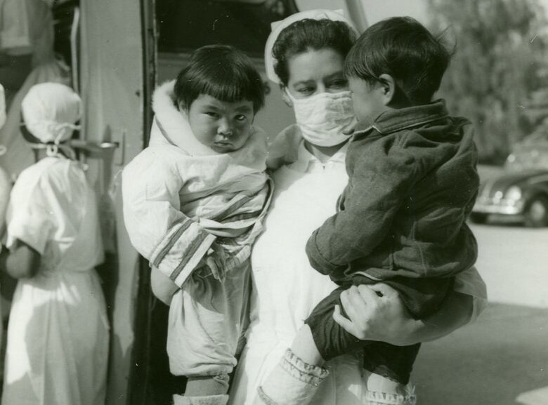 Nurse stands holding two babies