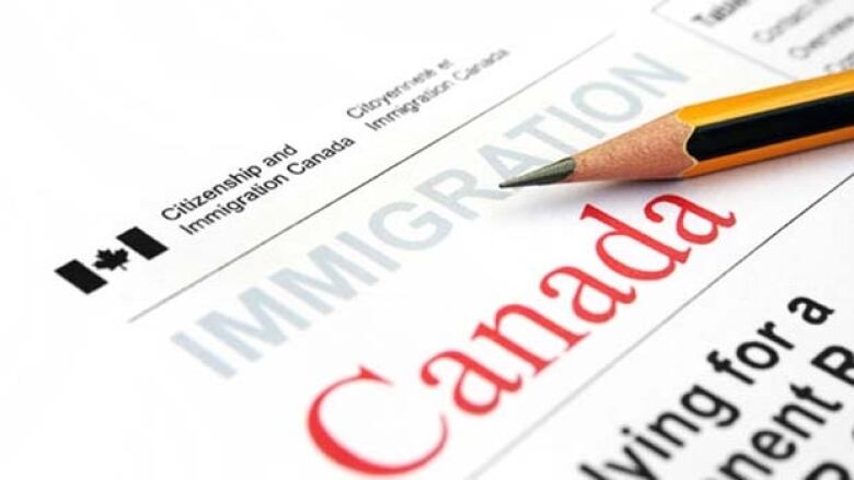 A pencil lies on top of an immigration form with a Canadian government logo. 