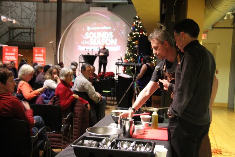 Male chef makes a dish as he's interviewed in front of an audience