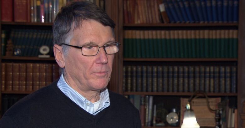 A police board member gives an interview in front of a bookshelf.