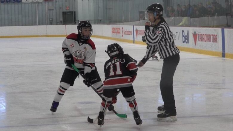 Two minor hockey players take a faceoff.