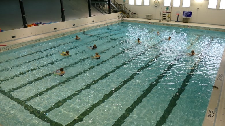 An indoor pool with people swimming.