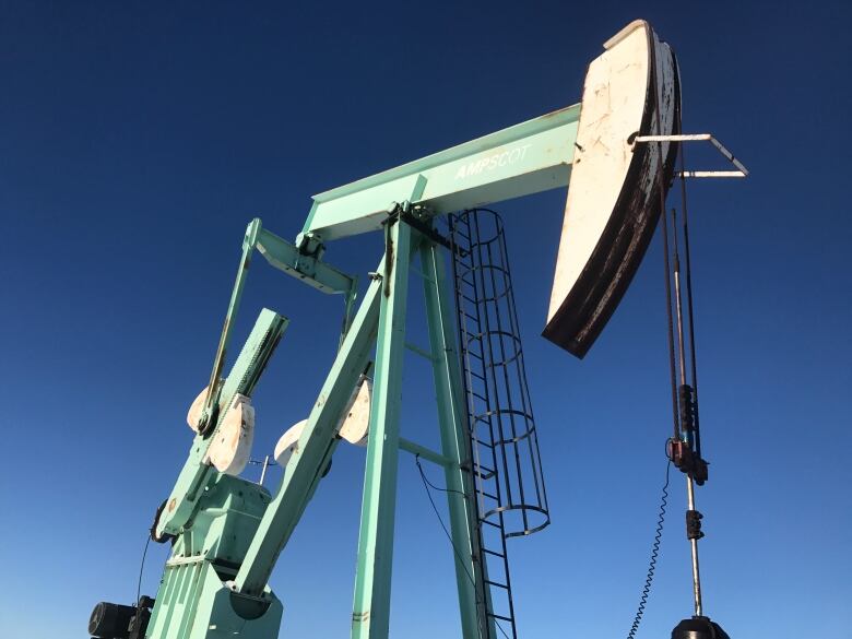 An oil pumpjack stands under a clear blue sky.