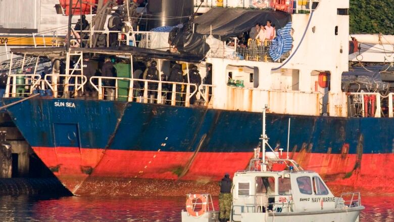 Migrants look over the side of the MV Sun Sea after it was escorted into CFB Esquimalt in Colwood, B.C., on Friday, Aug. 13, 2010.  The dilapidated cargo ship transported 492 Tamil migrants to Vancouver island.