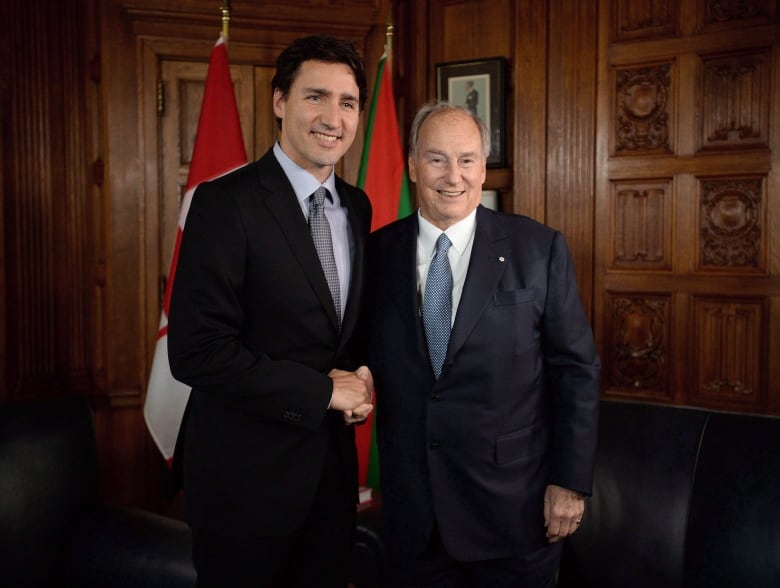 Two men in suits stand and face the camera.