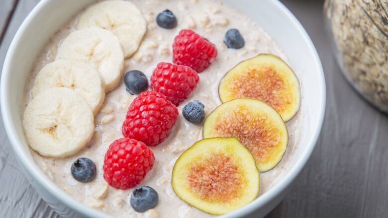 Overhead shot of a bowl of oatmeal with bananas, berries and fig slices on top. 