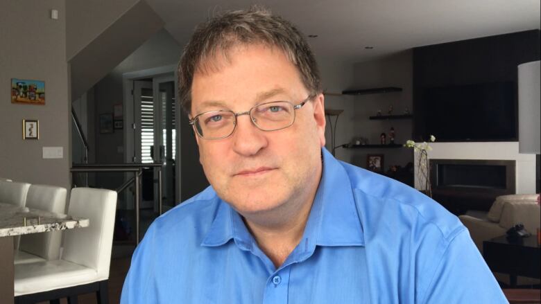 A white man with brown hair and a blue collared shirt.