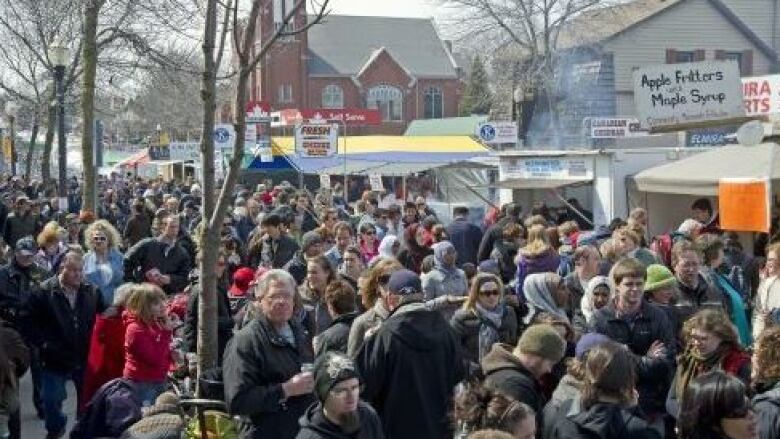 Crowd of people outside. Vendors under small tents are visible.