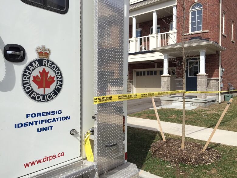 A police van and police tape in front of a home.