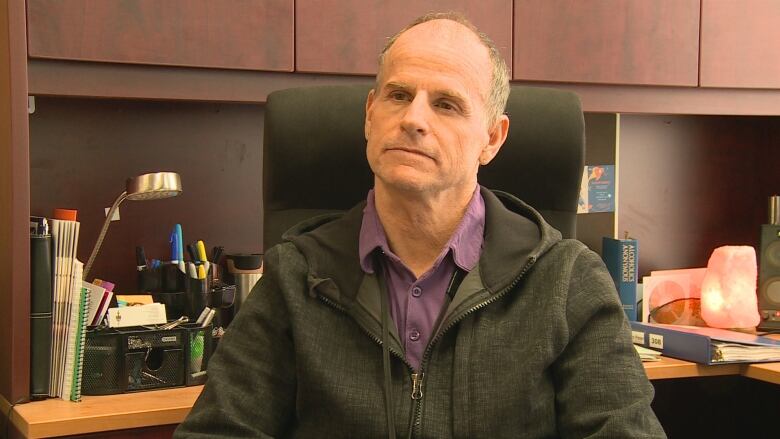 A man sits in chair in front of his office desk.