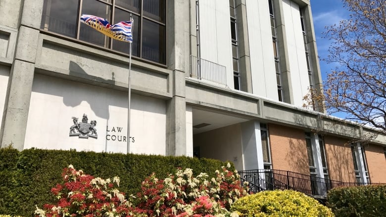 Victoria Law Courts is seen on a sunny day with a bush of flowers in front of it.