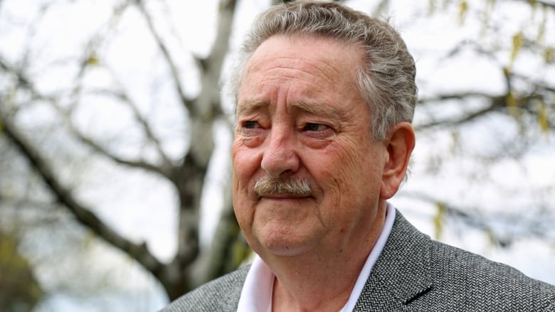 A headshot of a man wearing a suit who is outdoors.