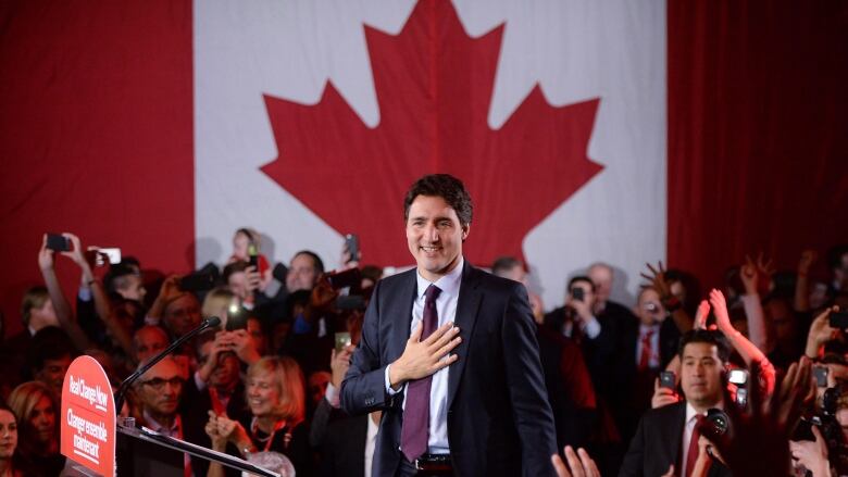 A man stands at a podium in front of a Canadian flag.