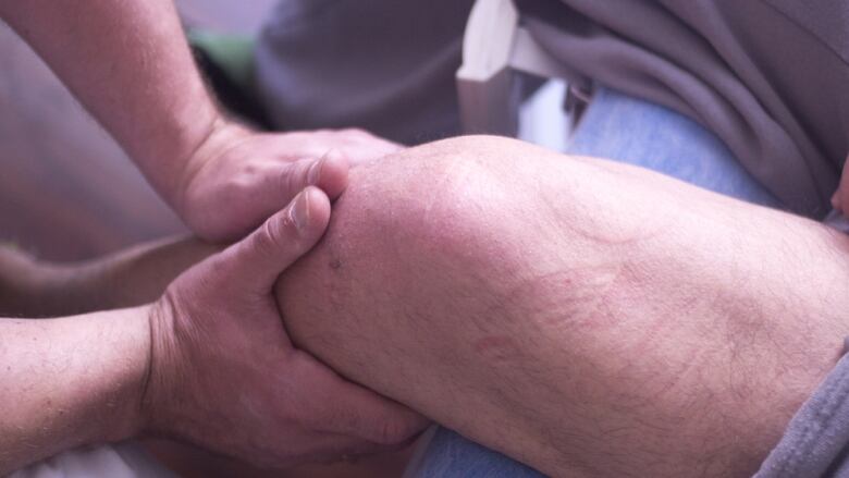 A pair of hands massage another person's leg.