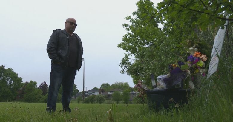 A man looks at a makeshift memorial in a park.