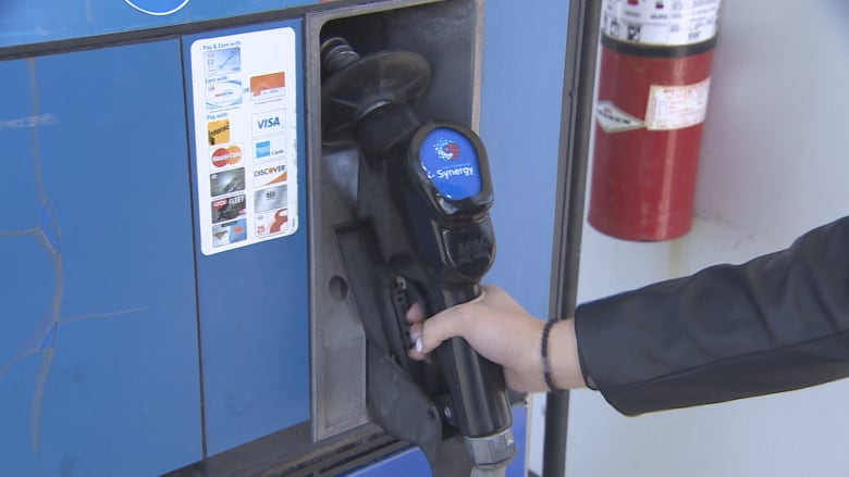 A hand reaches for a gas pump.