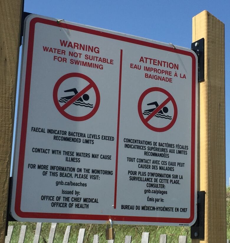 A large warning sign at a beach, indicating the water is not suitable for swimming.