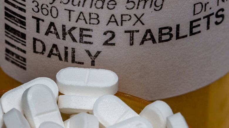 A pill bottle with a handful of pills in front of it.