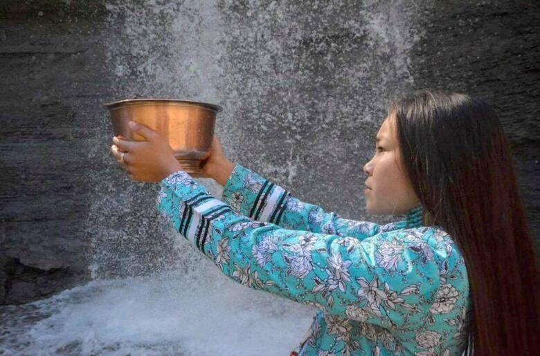 girl holds cup in water