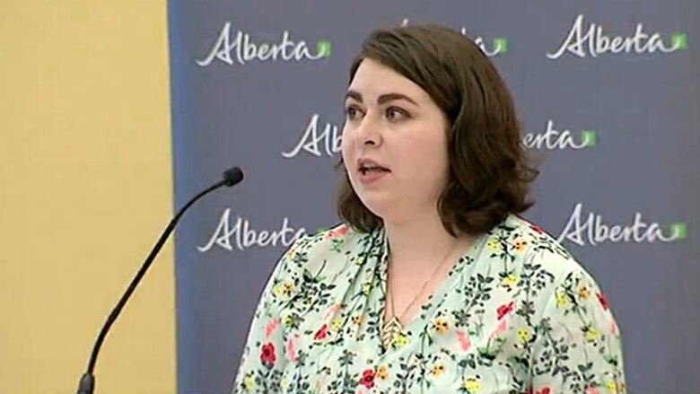 A woman speaks into a microphone at a meeting.