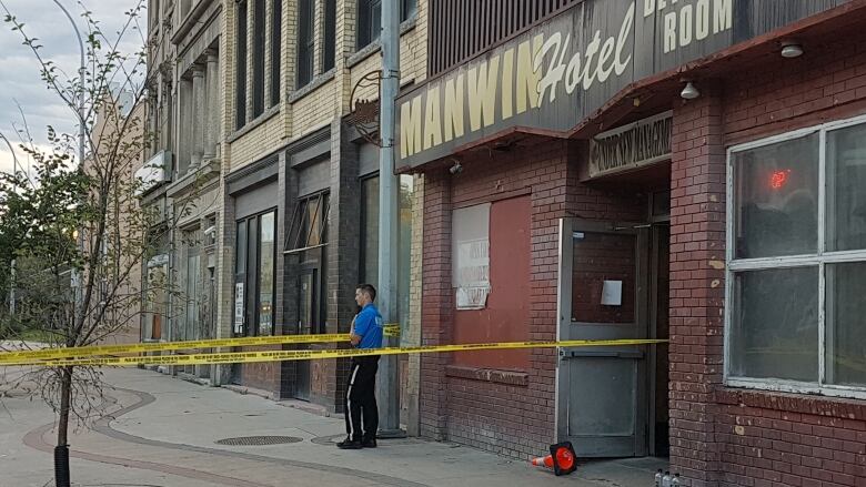 A police cadet guards the scene in front of the Manwin Hotel on Monday morning.