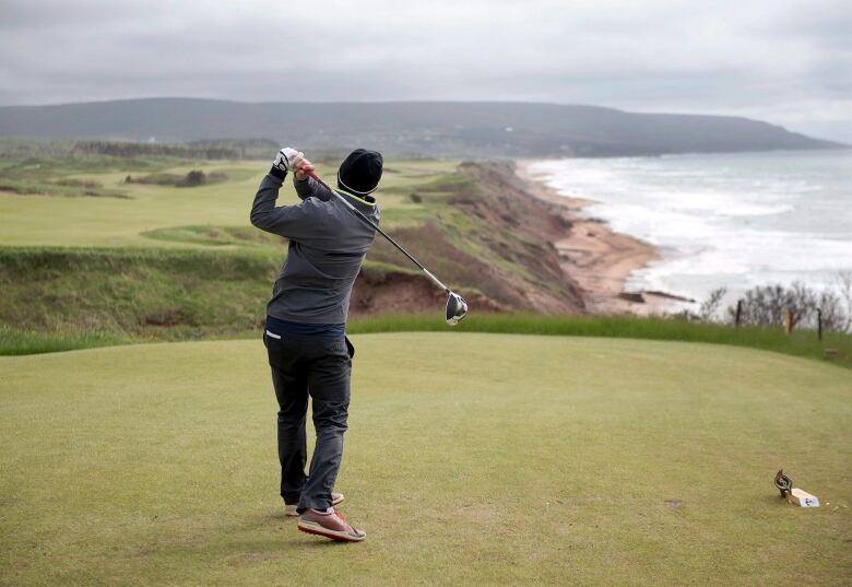 A man finishing a golf swing on a course